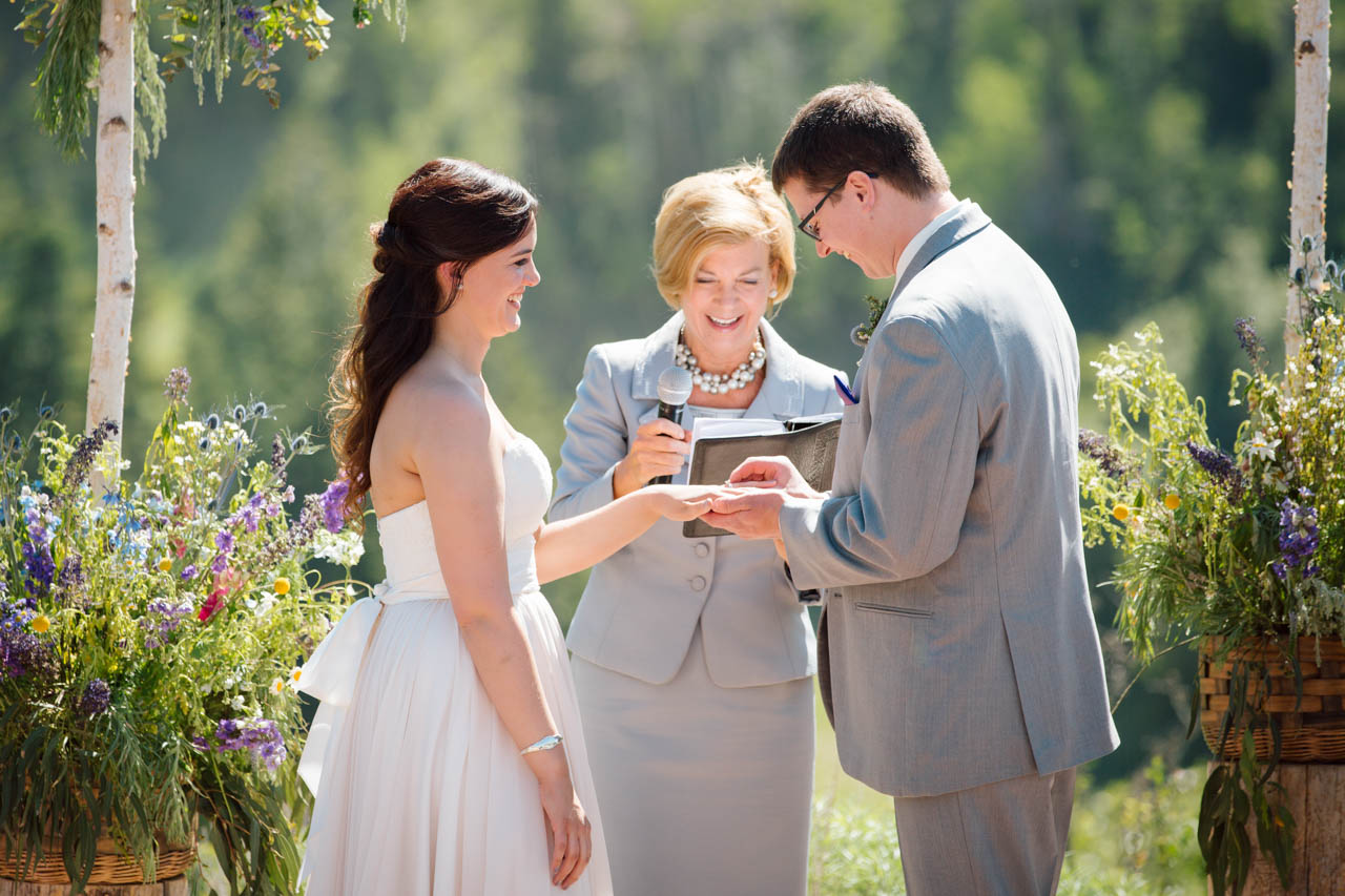 Wedding officiant smiles as the couple exchange rings.