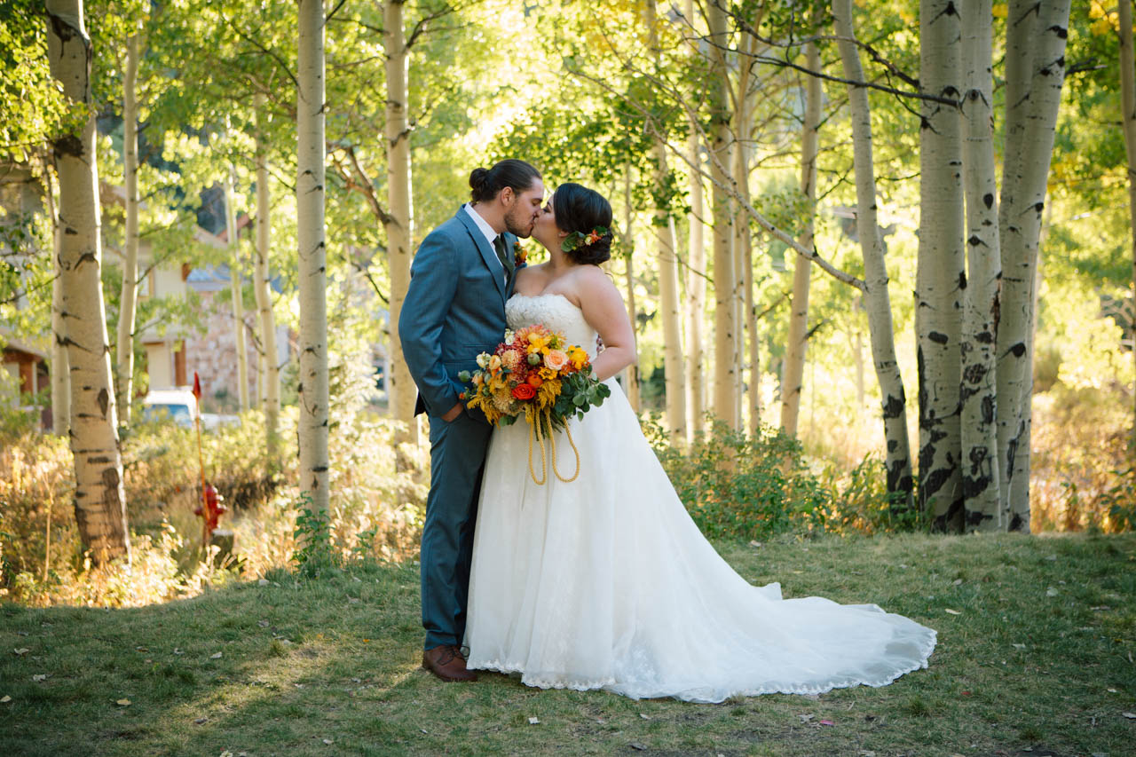 Newlywed couple kisses in the aspen trees at Silver Fork Lodge.